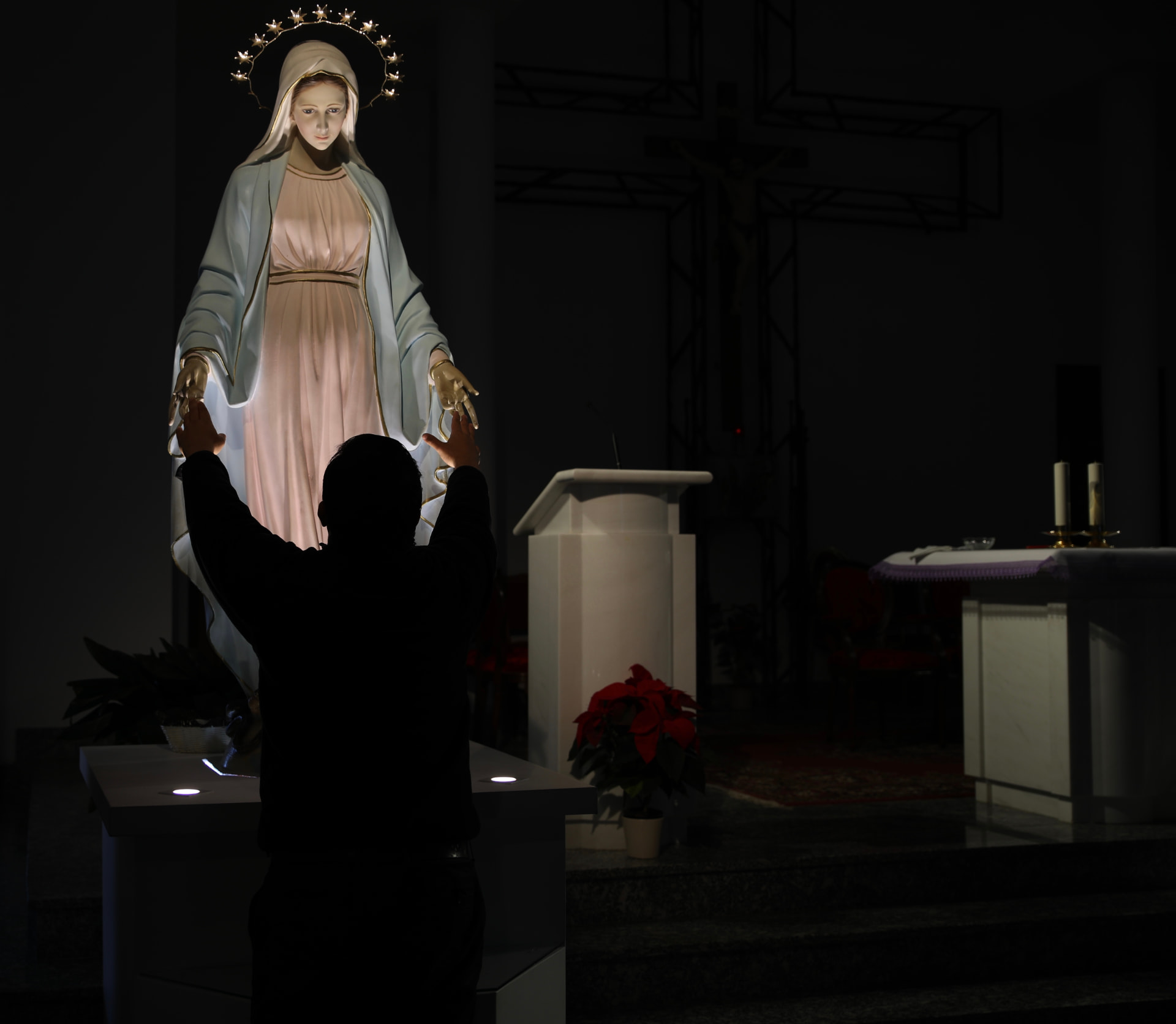 Frank Zapata con los brazos levantados ante una imagen iluminada de la Virgen Milagrosa